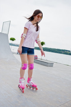 Portrait of a fabulous young woman rollerblading on the outdoor roller skating rink.