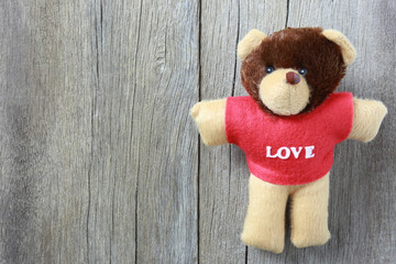 Teddy Bear is placed on old brown wood floor.