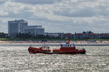 Fototapeta premium PILOT BOAT - Against the background of the sea coast and the buildings of Swinoujscie