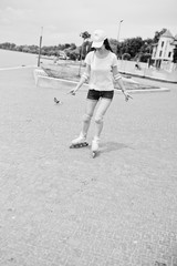 Portrait of a good-looking young woman in casual clothing rollerblading on the pavement in the park.  Black and white photo.