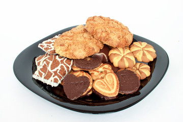 Different kinds cookies lying at the black plate.