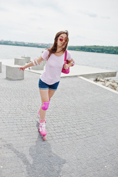 Portrait of a good-looking young woman in casual clothing rollerblading on the pavement in the park.