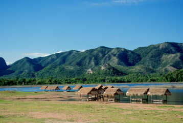 Fototapeta na wymiar Small huts at lake shore surrounded by mountains