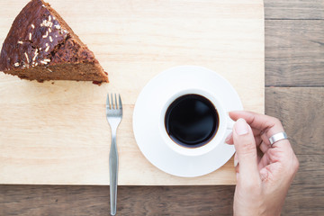 Creative flat lay of woman hand with coffee cup and chocolate cake