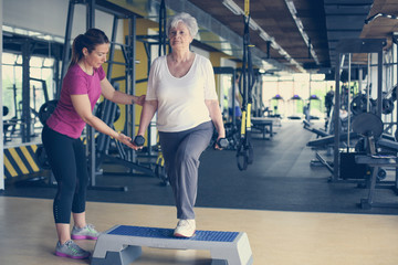 Fototapeta na wymiar Personal trainer working exercise with senior woman in the gym. Senior woman lift weight.