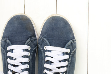 Old sneakers on white wooden floor background.