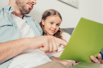 Obraz premium smiling little girl doing homework with father