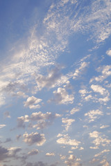 Breathtaking big and small cumulus clouds on the light-blue sky. Vertical image