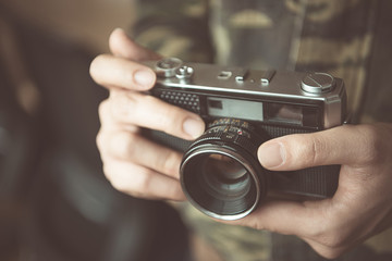 Vintage photo camera in the hands of man, soft focus.