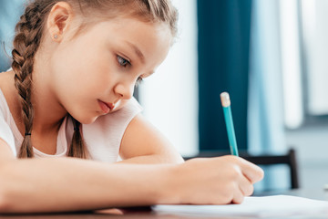 Focused serious little girl writing homework