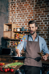 handsome excited man with apron frying vegetables