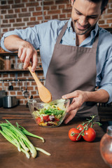 happy young man mixing salad