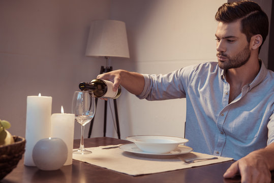 mna pouring wine in glass for romantic dinner