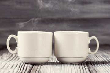 Two cups of hot coffee over wooden background