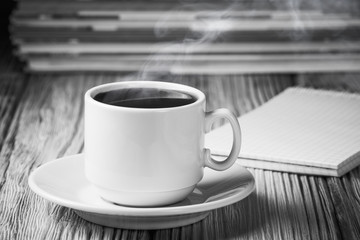 Hot cup of coffee over blank sketchbook and pile of books