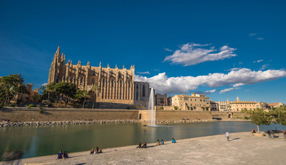 Panoramic view Palma de Mallorca Cathedral blue sky reflected in water Tourists and people walking and taking photos. Balearic islands of Spain