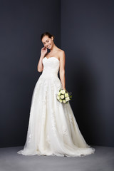 Fototapeta premium Beautiful bride smiling in white wedding dress, studio