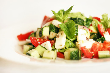 Salad of cucumbers, tomatoes, mozzarella cheese, lettuce, onions, spices and olive oil. Healthy food. Tomato, cucumber, mozzarella cheese, onion, lettuce.