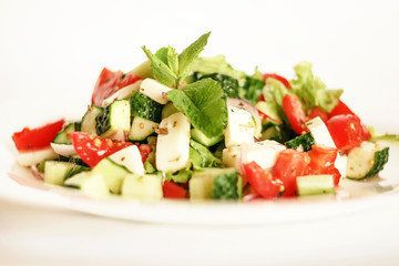 Salad of cucumbers, tomatoes, mozzarella cheese, lettuce, onions, spices and olive oil. Healthy food. Tomato, cucumber, mozzarella cheese, onion, lettuce.