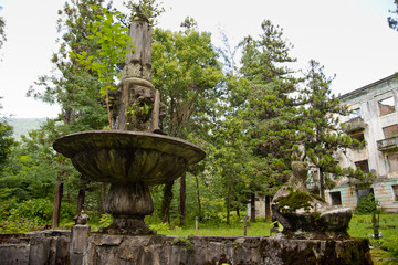 The abandoned miner's ghost town Tquarchal (Tkvarcheli, Abkhazia). Idle fountain on the background of a ruined house