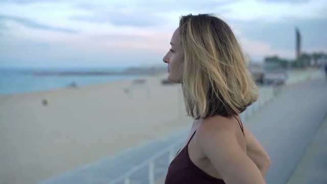 Pensive woman admire view standing near beach in city
