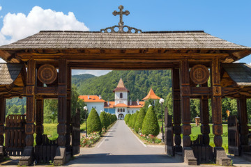Wooden entrance gate and road to Brancoveanu monastery in Sambata de Sus village, Romania