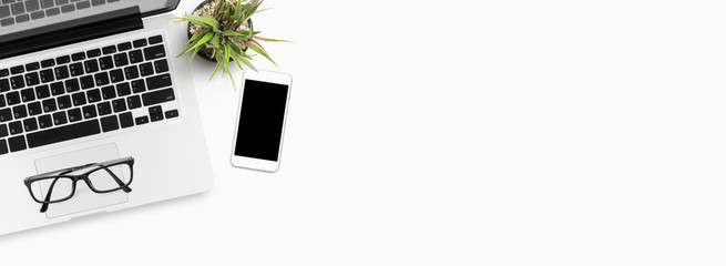 White office desk table with laptop and smartphone. Top view with copy space, flat lay. This can be used to create a website header.