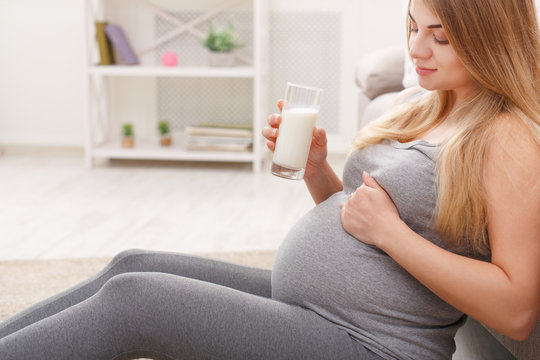 Pregnant woman drinking glass of milk copy space