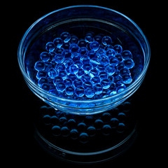 Blue hydrogel balls in a glass vase isolated on a black background