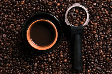 A cup of black coffee with coffee bean as background