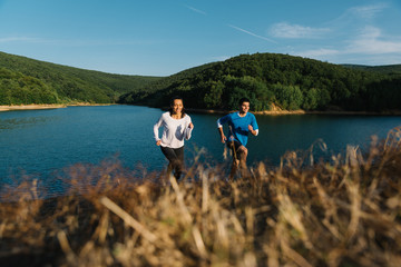 Couple having fun racing uphill from a lake shore