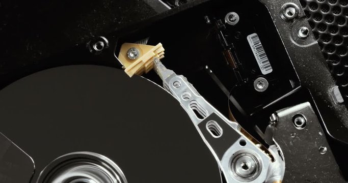 HDD reading and writing data. Operating hard disk drive on dark background.