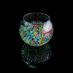 Colored hydrogel balls in a glass vase isolated on a black background