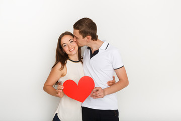 Young happy couple in love holding red paper heart