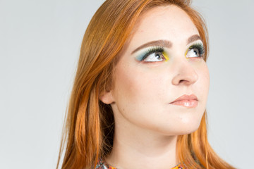 Naklejka premium Young girl is looking upwards and with puzzled look. Redheaded girl wearing colorful yellow dress. Summer..
