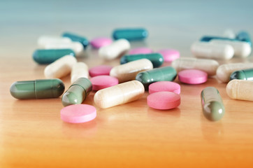 Pharmacy theme. Multicolored pills on a brown wooden surface. Closeup.