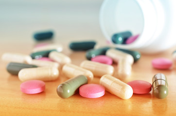 Pharmacy theme. White bottle of multicolored pills on a wooden surface. Closeup.