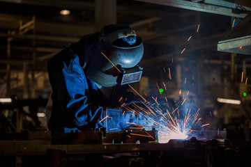 Worker is welding in car factory