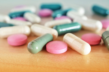 Pharmacy theme. Multicolored pills on a brown wooden surface. Closeup.