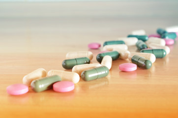 Pharmacy theme. Multicolored pills on a brown wooden surface. Closeup.