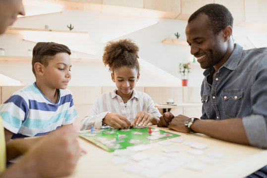 african-american family playing board game in cafe