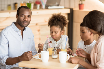 Fototapeta na wymiar african-american family eating delicious desserts in cafe
