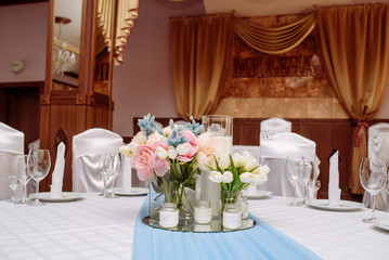 Fresh spring tulips and candles in glasses. Covered festive table. Bride idea.
