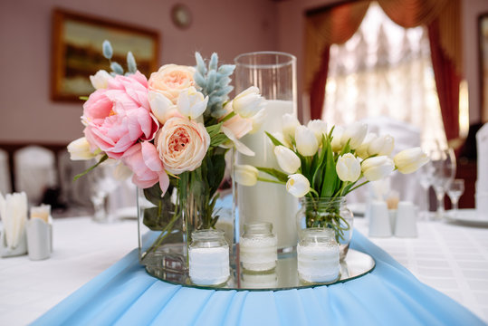 Fresh spring tulips and candles in glasses. Covered festive table. Bride idea.