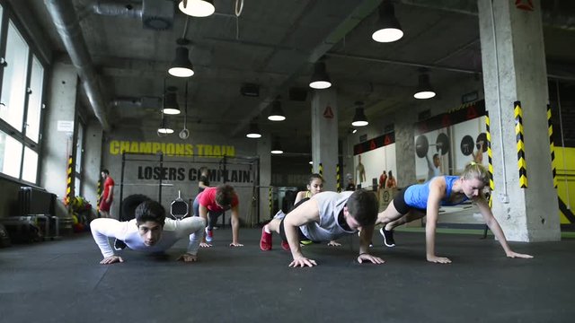 Young people in crossfit gym doing push ups.