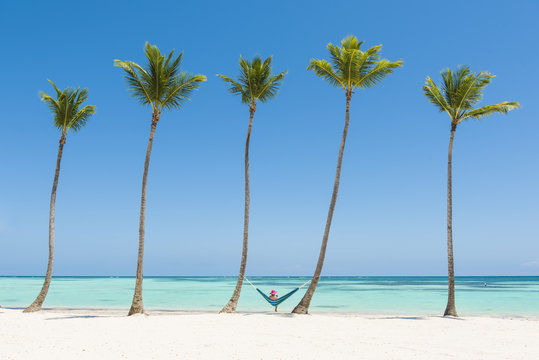 Fototapeta Woman relaxing on a hammock on a palm-fringed beach