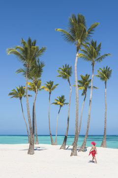 Juanillo Beach (playa Juanillo), Punta Cana, Dominican Republic. Woman walking on a palm-fringed beach (MR).