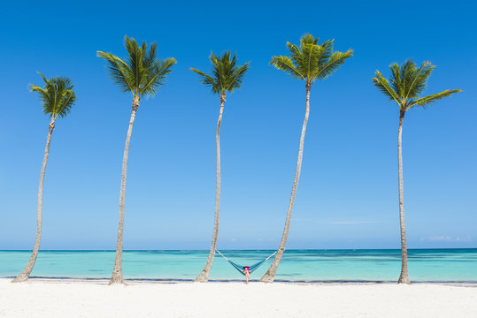 Juanillo Beach (playa Juanillo), Punta Cana, Dominican Republic. Woman relaxing on a hammock on a palm-fringed beach (MR).