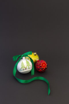 Beautiful white, red and green christmas balls with green silky ribbon on black background.