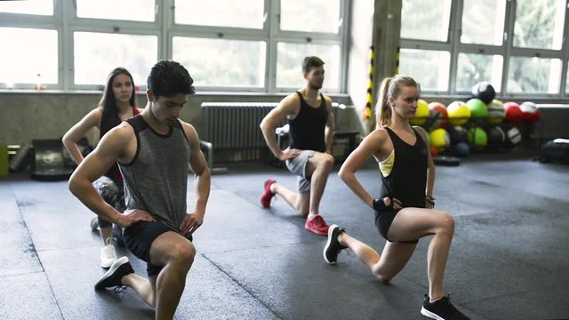 Young people in crossfit gym in lunge position.